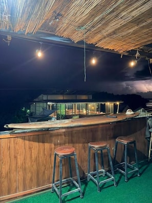Zona de bar con taburetes, una barra y vistas al mar.