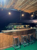 Zona de bar con taburetes, una barra y vistas al mar.