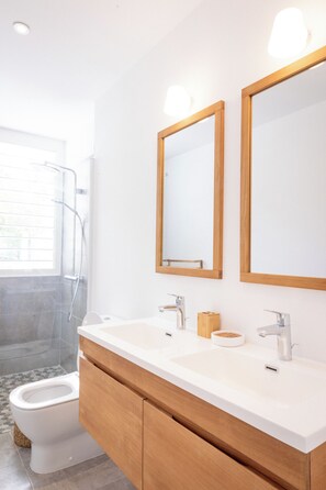 A modern bathroom with a shower, toilet, and vanity with two mirrors. - Ti Soleil: Exceptional Ocean View (Les Anses-d'Arlet)