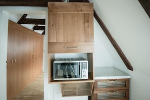 A kitchen with wooden cabinets, a microwave, and a countertop. - Charles Bridge Hostel & Apartments (Prague)