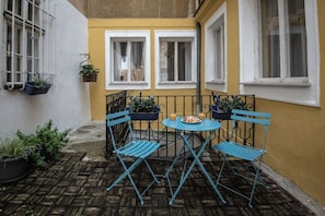 A small outdoor seating area with a table and chairs, potted plants, and a yellow wall. - Charles Bridge Hostel & Apartments (Prague)