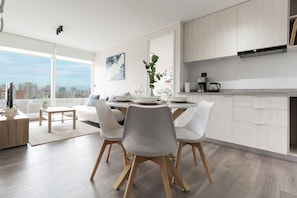 A modern kitchen with a dining area, large windows, and a city view. - Dos Norte 1230 (Viña del Mar)