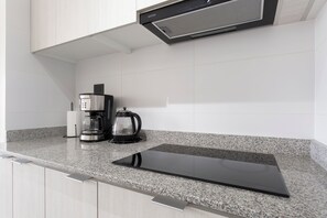 A kitchen with a built-in coffee maker, a kettle, and a sleek black countertop. - Dos Norte 1230 (Viña del Mar)