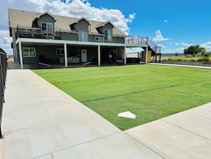 A residential property with a covered patio, a well-maintained lawn, and a two-story house with a balcony. - Zion Luxury Retreat | 6BR Pool Pickleball Hot tub (Colorado City)