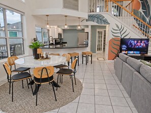 A modern kitchen with a dining area, a staircase, and a television. - Paddle Point | Weeki Wachee Main River & Kayaks (Weeki Wachee)