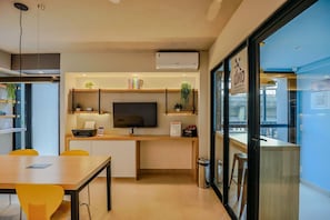 A modern kitchen with a flat-screen TV, a coffee machine, and a small plant on the counter. - Studio Metr Santa Cec lia Piscina e Rooftop (São Paulo)