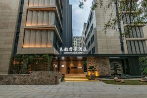 A modern hotel entrance with a stone facade, a wooden slatted entrance, and a well-lit pathway leading to the door. - Ssaw Boutique Hotel Hangzhou Liangyun (Hangzhou)