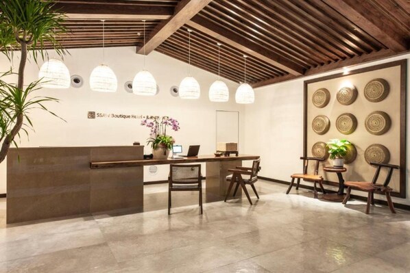 A reception area with a wooden reception desk, several chairs, hanging pendant lights, and a wall with decorative plates. - Ssaw Boutique Hotel Hangzhou Liangyun (Hangzhou)