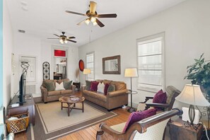 Ein Wohnzimmer mit zwei Sofas, einem Couchtisch, einer Stehlampe, einem Beistelltisch und einem Deckenventilator.