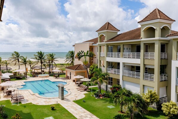 A resort with a swimming pool, outdoor seating, and a view of the beach. - Atlantic Apart Hotel - Porto das Dunas (Aquiraz)