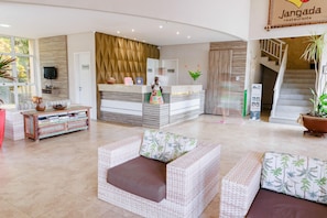 A hotel lobby with wicker furniture, a reception desk, and a staircase. - Atlantic Apart Hotel - Porto das Dunas (Aquiraz)
