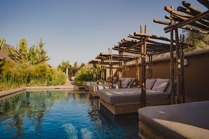 Ein Poolbereich mit Liegestühlen und einer Pergola.