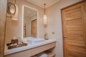 A bathroom with a white sink, wooden vanity, and a large mirror. - Casa Molle (Vicuña)