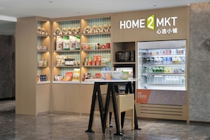 A Home 2 MKT store with shelves stocked with pet food, a microwave, and a refrigerator. - Home2 Suites by Hilton Hengyang Zhengxiang (Hengyang)