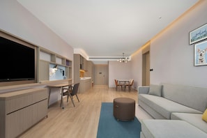 Una sala moderna con un televisor de pantalla plana, un comedor con mesa y sillas, y un sofá.