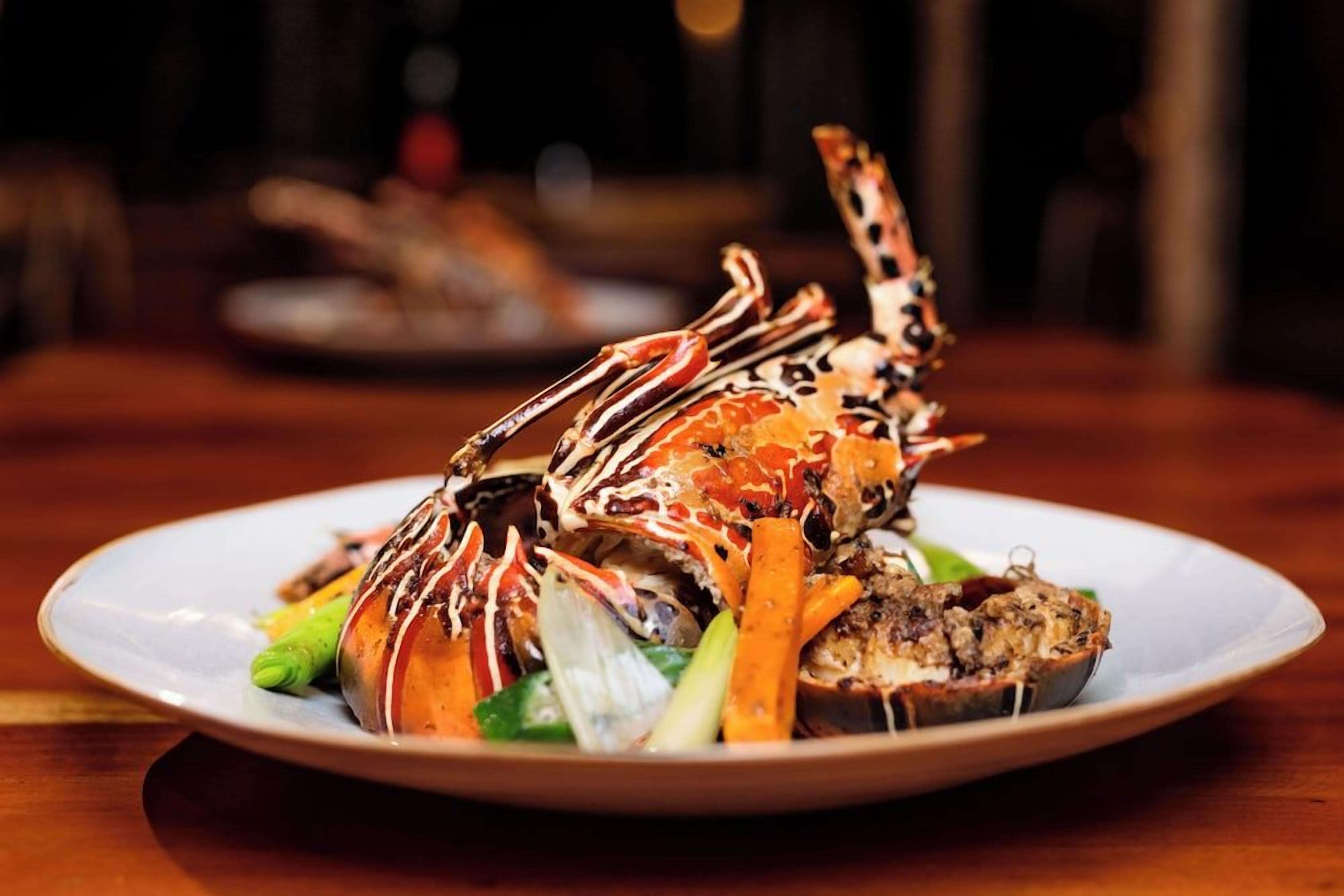 A plate with a lobster tail, vegetables, and a piece of bread.