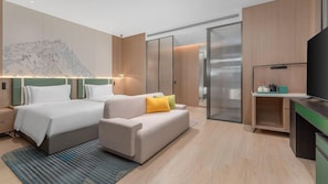 Una habitación de hotel con dos camas, un sofá, un televisor y una kitchenette.