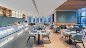 Un restaurante moderno con una barra alargada, varias zonas de estar y amplios ventanales.
