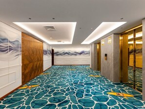 A hotel corridor with patterned carpet, wooden panel walls, and a modern ceiling design. - Gateway Palolem Goa (Canacona)