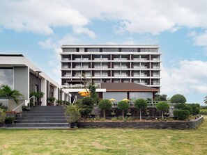 A multi-story hotel with a modern design, featuring a central staircase, outdoor seating area, and a well-maintained lawn. - Gateway Palolem Goa (Canacona)