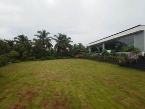 A modern building with a large glass facade, surrounded by a well-maintained lawn and palm trees. - Gateway Palolem Goa (Canacona)