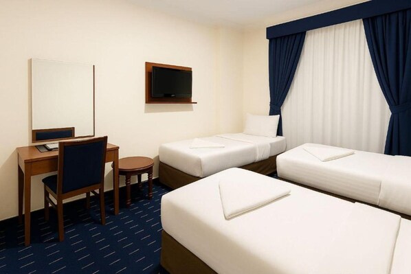 A hotel room with two single beds, a desk with a chair, a television, and a small table. - Jawaher Albait Hotel Makkah (Makkah)