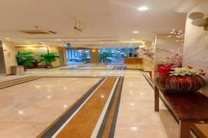 A hotel lobby with a marble floor, potted plants, a reception desk, and a decorative vase. - Jawaher Albait Hotel Makkah (Makkah)