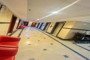 A hotel corridor with a tiled floor, red seating, and doors leading to rooms. - Jawaher Albait Hotel Makkah (Makkah)