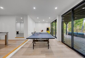 Een tafeltennistafel in een moderne kamer met grote ramen en uitzicht op het landschap.