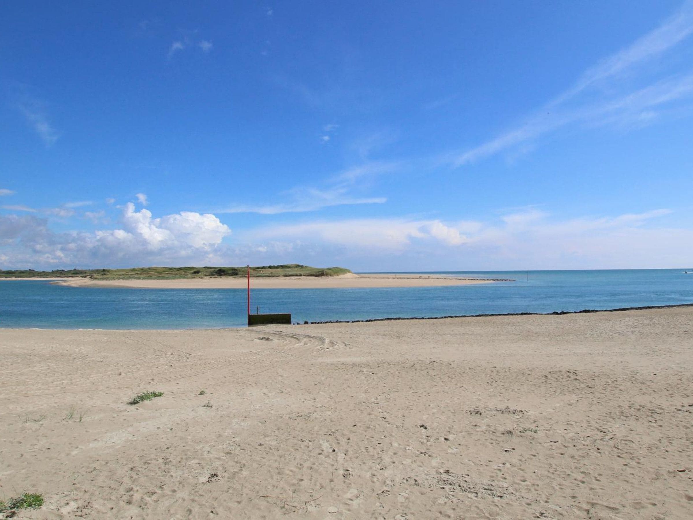 A beach with a clear sky, a sandy shore, and a calm sea.