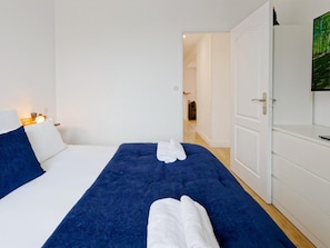 A hotel room with a bed, a bedside table with a lamp, a wardrobe, and a door leading to another room. - Cozy apartment with AC - 2 guests (Portbail)