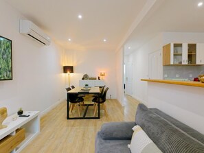 A modern living space with a dining area, a sofa, and a kitchen. - Cozy apartment with AC - 2 guests (Portbail)