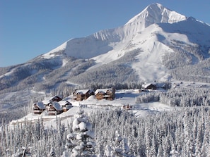 A snow-covered mountain with a lodge complex in the foreground. - Cozy Big Sky 5 bedroom home with private Lodge access, ski in/out, NEW RELEASE (Big Sky)