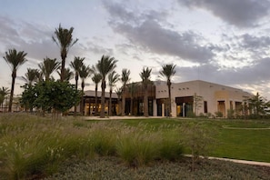 A modern building with a flat roof, surrounded by palm trees and a grassy area. - Daraah Resort (Al Wajh)