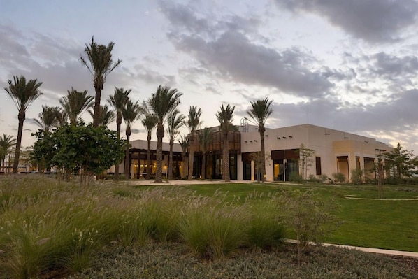 A modern building with a flat roof, surrounded by palm trees and a grassy area. - Daraah Resort (Al Wajh)