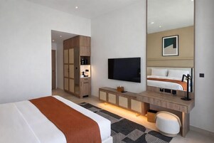 Una habitación de hotel moderna con una cama grande, televisión, armario y escritorio con espejo.