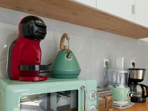 A kitchen with a vintage-style microwave, a red coffee maker, a green kettle, and a food processor. - Apartment with AC and spa in picturesque village (Portbail)