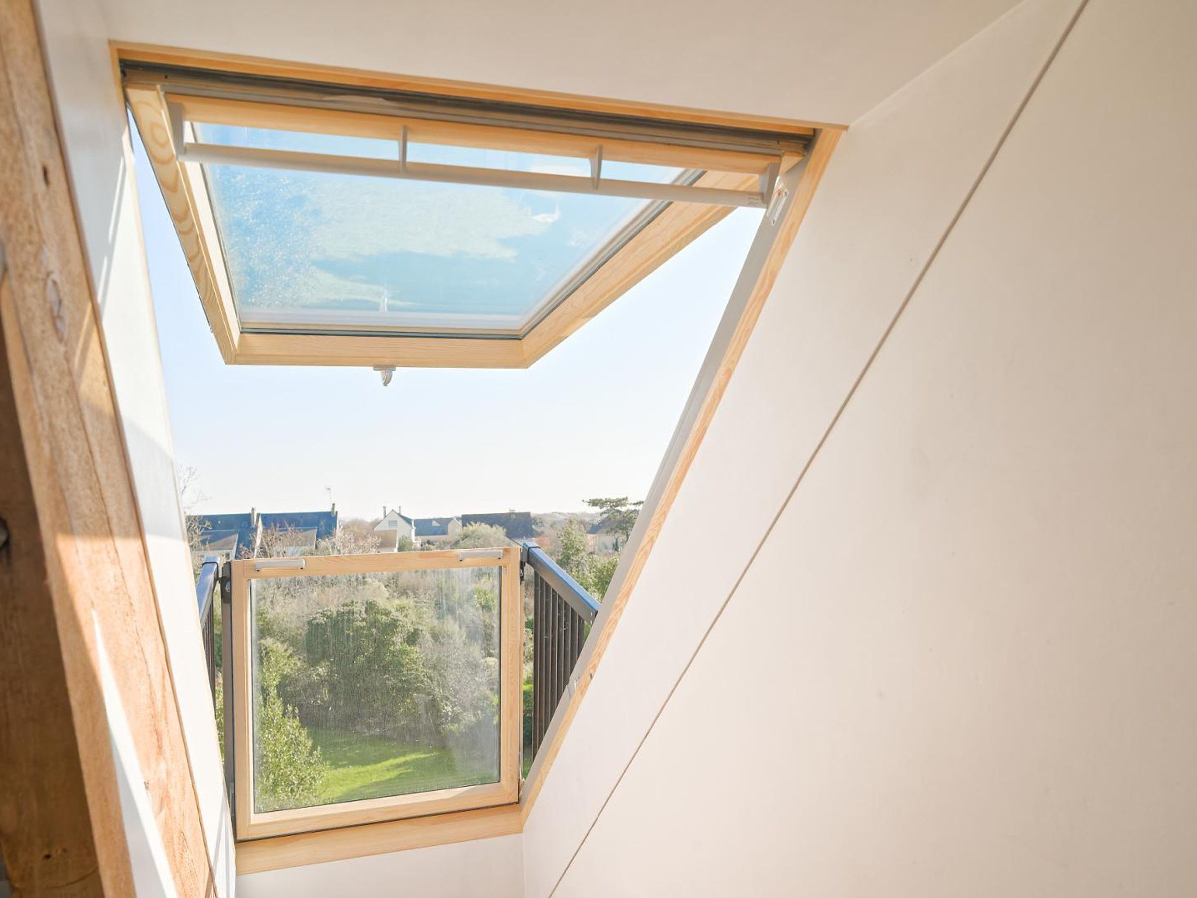 A skylight window with a view of a green landscape and buildings in the distance.