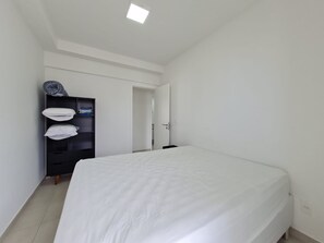 Ein schlicht eingerichtetes Schlafzimmer mit Bett, Kleiderschrank und einer Tür zu einem anderen Raum.