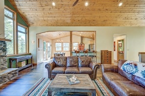 A spacious living room with leather sofas, a coffee table, and a stone fireplace. - Ruby Mountain House With EV Charger (Buena Vista)