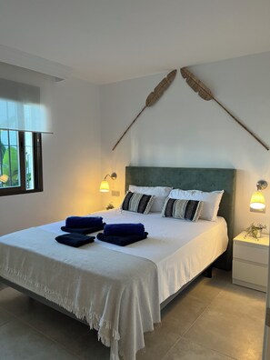 A neatly made bed with a white and blue bedspread, two bedside lamps, and a decorative feather on the wall. - Family Garden Retreat-Las Farolas-Mijas Costa (AN)