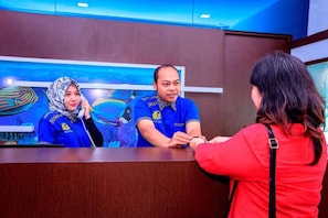 A reception desk with a wooden counter and a blue wall with a fish mural. - Aquatel Hotel (Pekanbaru)