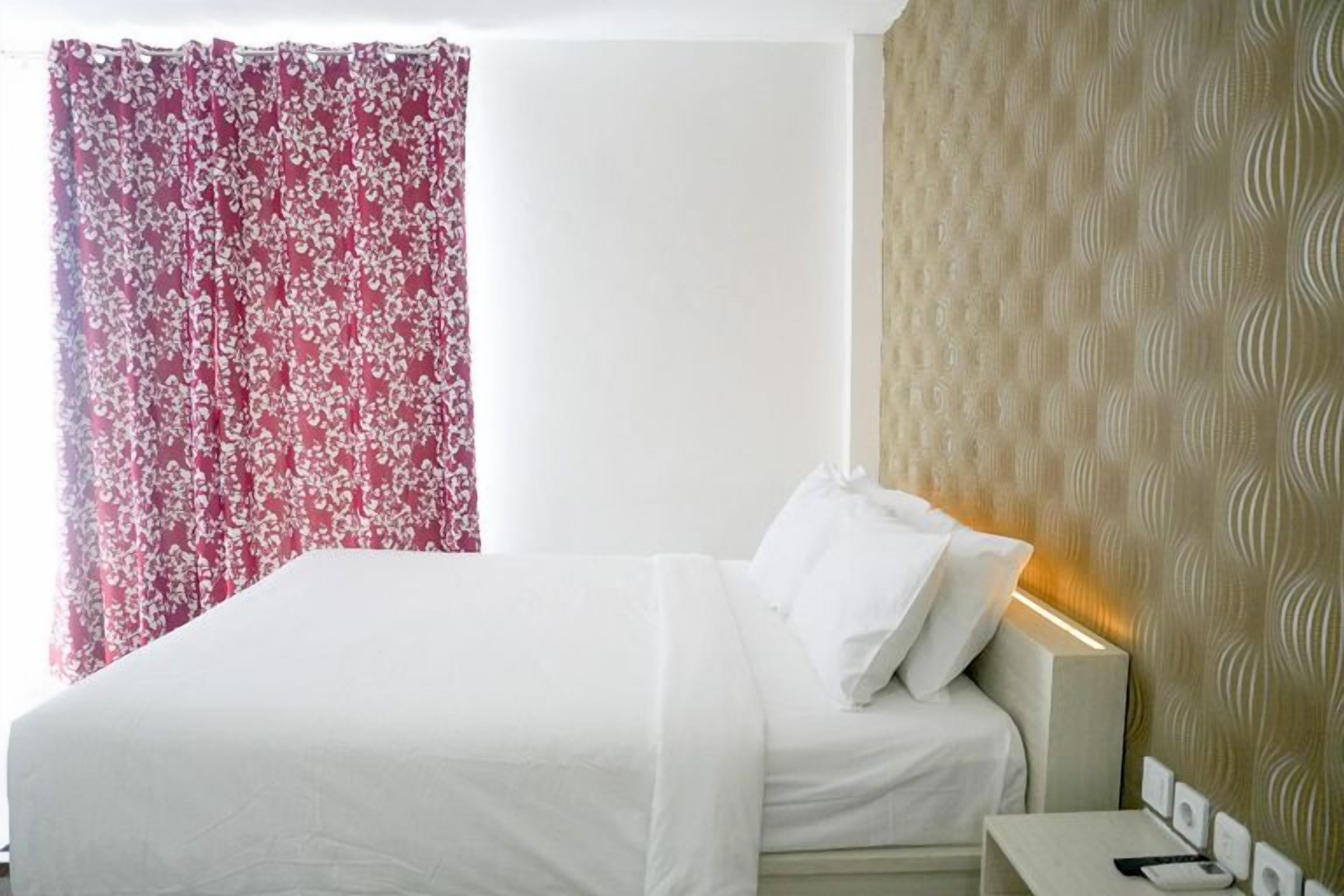 A hotel room with a bed, a nightstand, and a wall with a textured pattern.