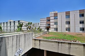 Ein mehrstöckiges Gebäude mit flachem Dach und einem Parkplatz davor.