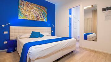 Una camera da letto con un letto grande, una parete azzurra e un quadro astratto colorato.
