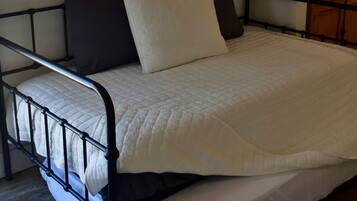 A bed with a metal frame, white bedding, and a single pillow.