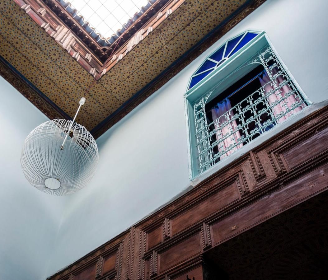 A room with a patterned ceiling, a hanging light fixture, and a window with a decorative grille.