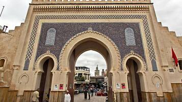 A large archway with intricate tile work and a flag on the right.