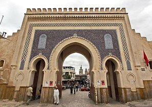 A large archway with intricate tile work and a flag on the right. - Dar Anne – Traditional Guesthouse in Fez (Fès)