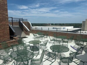 An outdoor patio with multiple round tables and chairs, a brick wall, and a staircase leading to a higher level. - Lexington luxury -Walk to Rupp-2 parking spaces (Lexington)